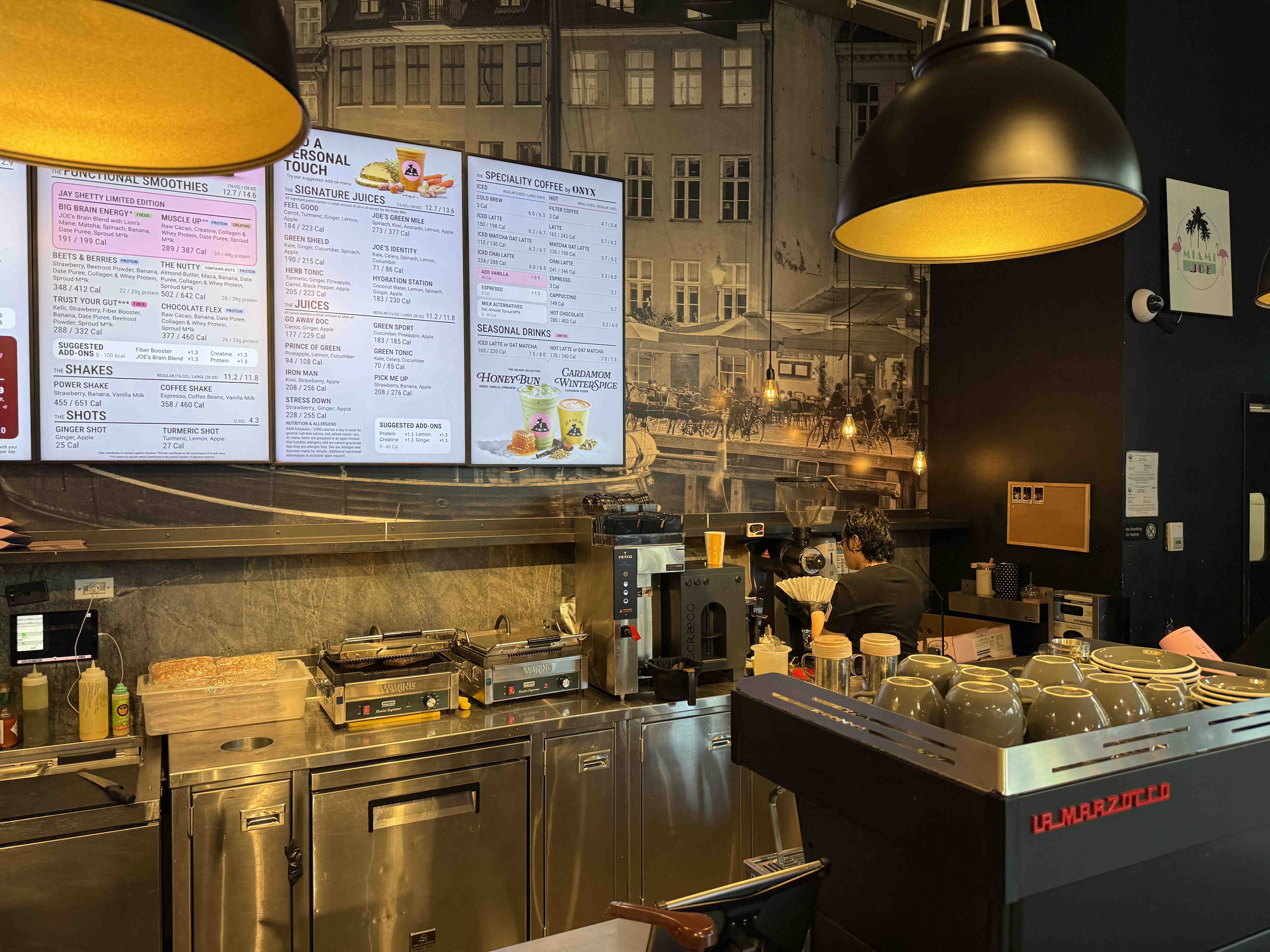 Barista u kávovaru pod menu obrazovkami FUNCTIONAL SMOOTHIES a SPECIALITY COFFEE @ ONYX.