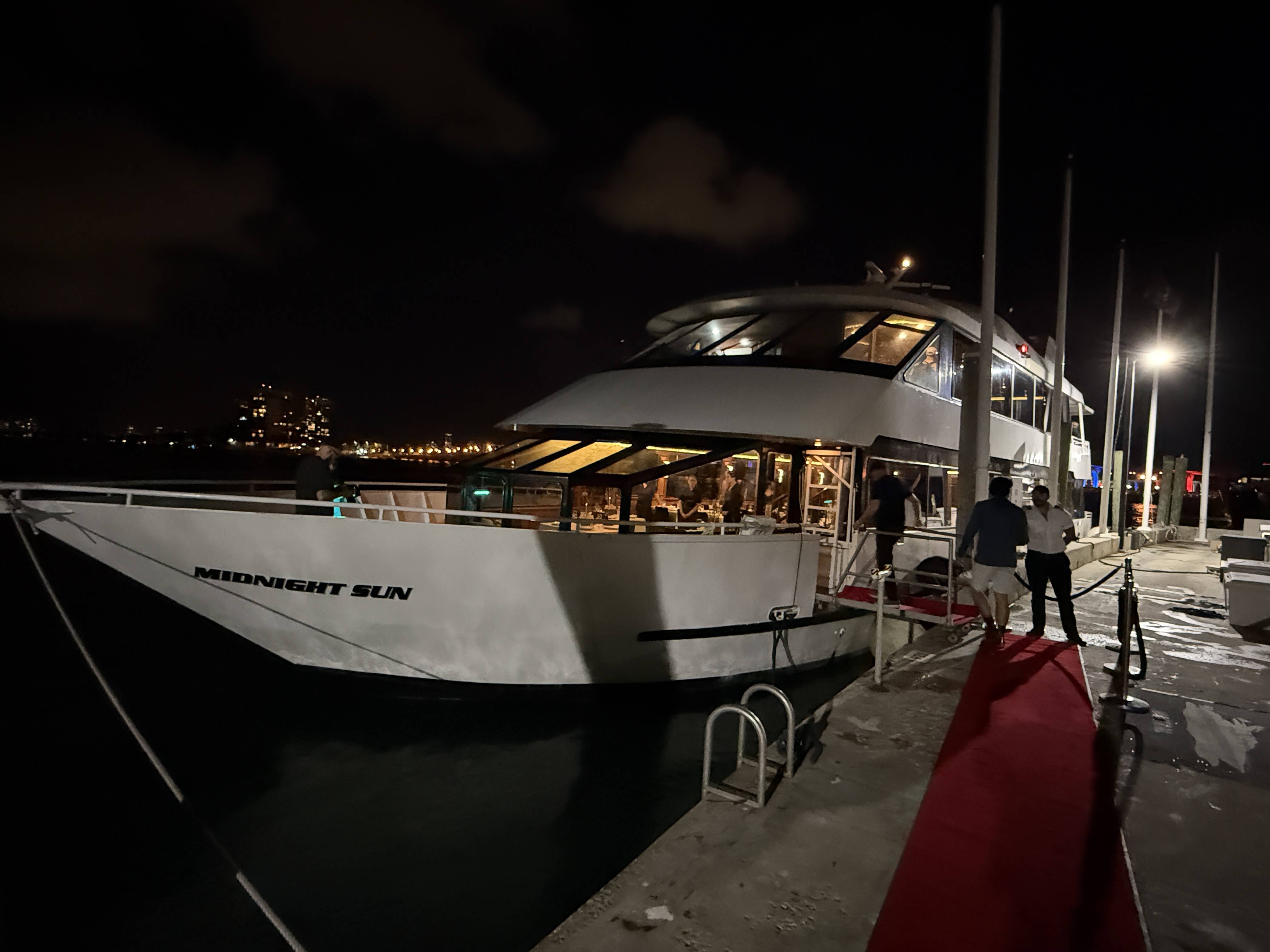 Noční jachta MIDNIGHT SUN u mola, lidé nastupují po červeném koberci.