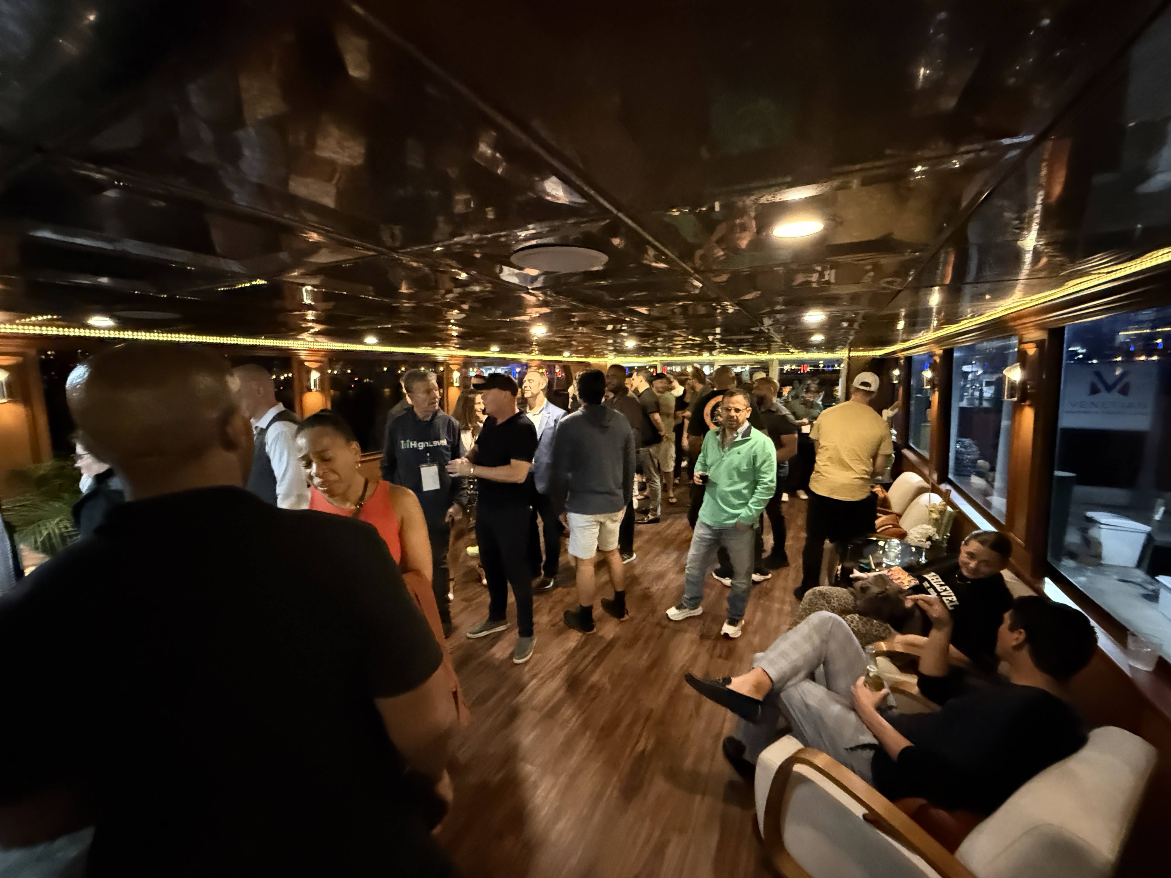 Networking na palubě lodi, skupiny lidí, tričko HighLevel, cedule VENEZIA.