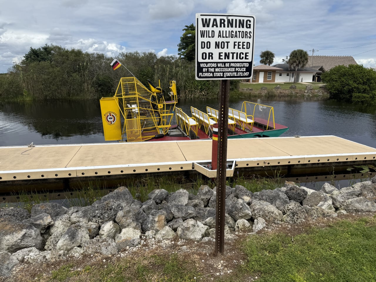 Cedule varuje před aligátory u dokovacího mola s airboatem na kanálu.