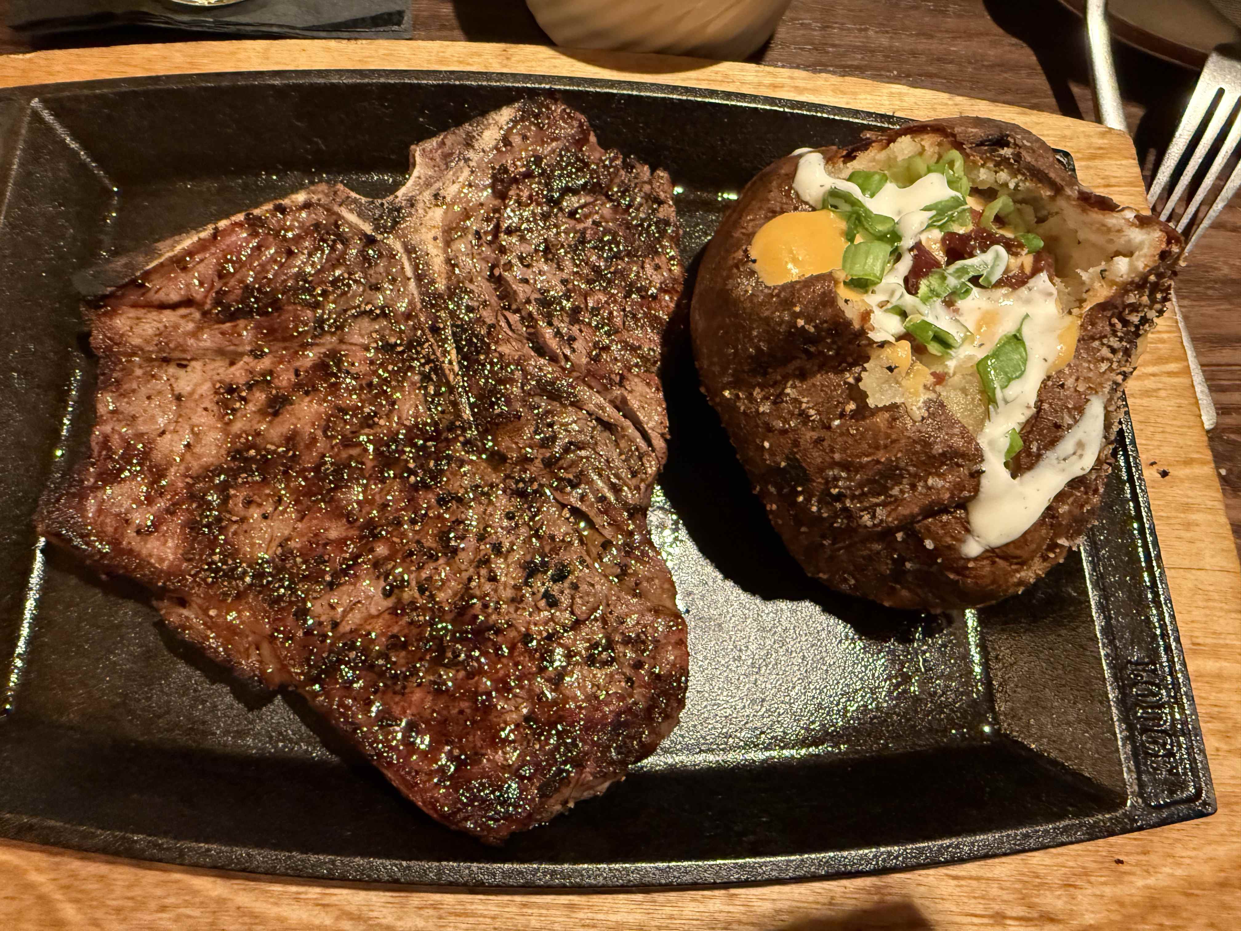 Hovězí steak na litinové pánvi s plněným pečeným bramborem a omáčkou