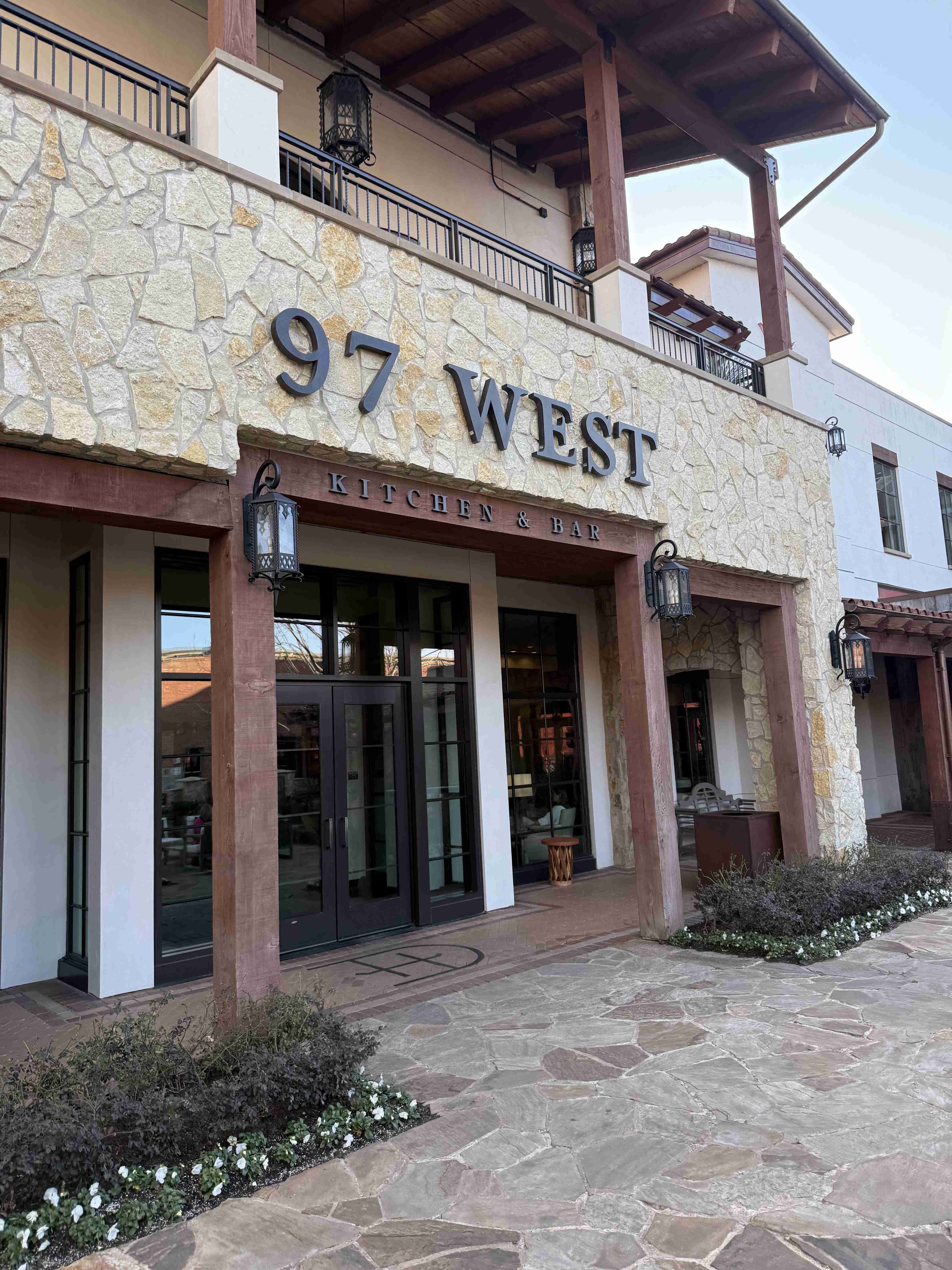 Fasáda restaurace 97 WEST, nápis KITCHEN & BAR nad vstupem.