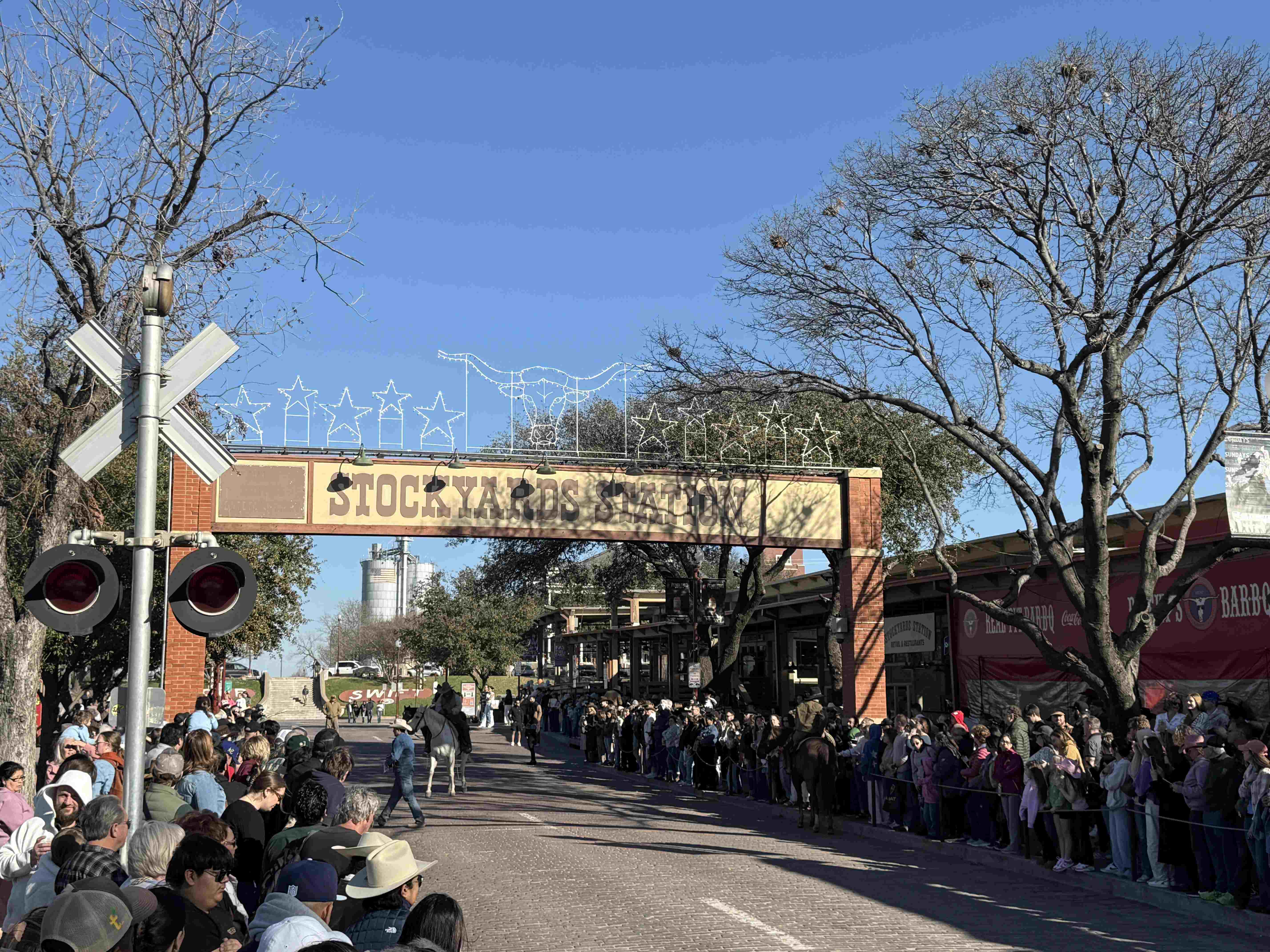 Dav u brány STOCKYARDS STATION sleduje průvod kovbojů na koních