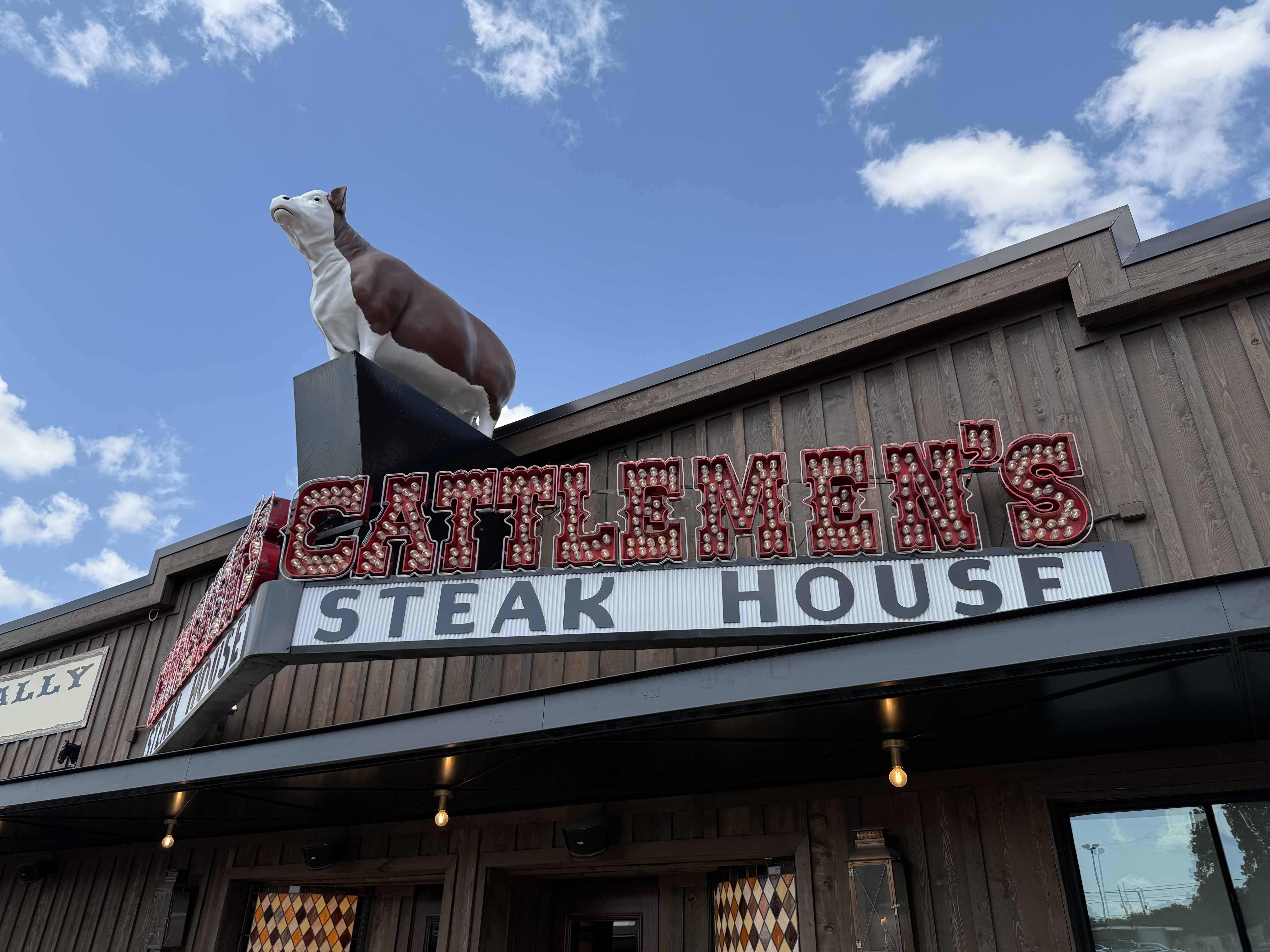 Socha krávy na střeše a nápis CATTLE MEN'S STEAK HOUSE