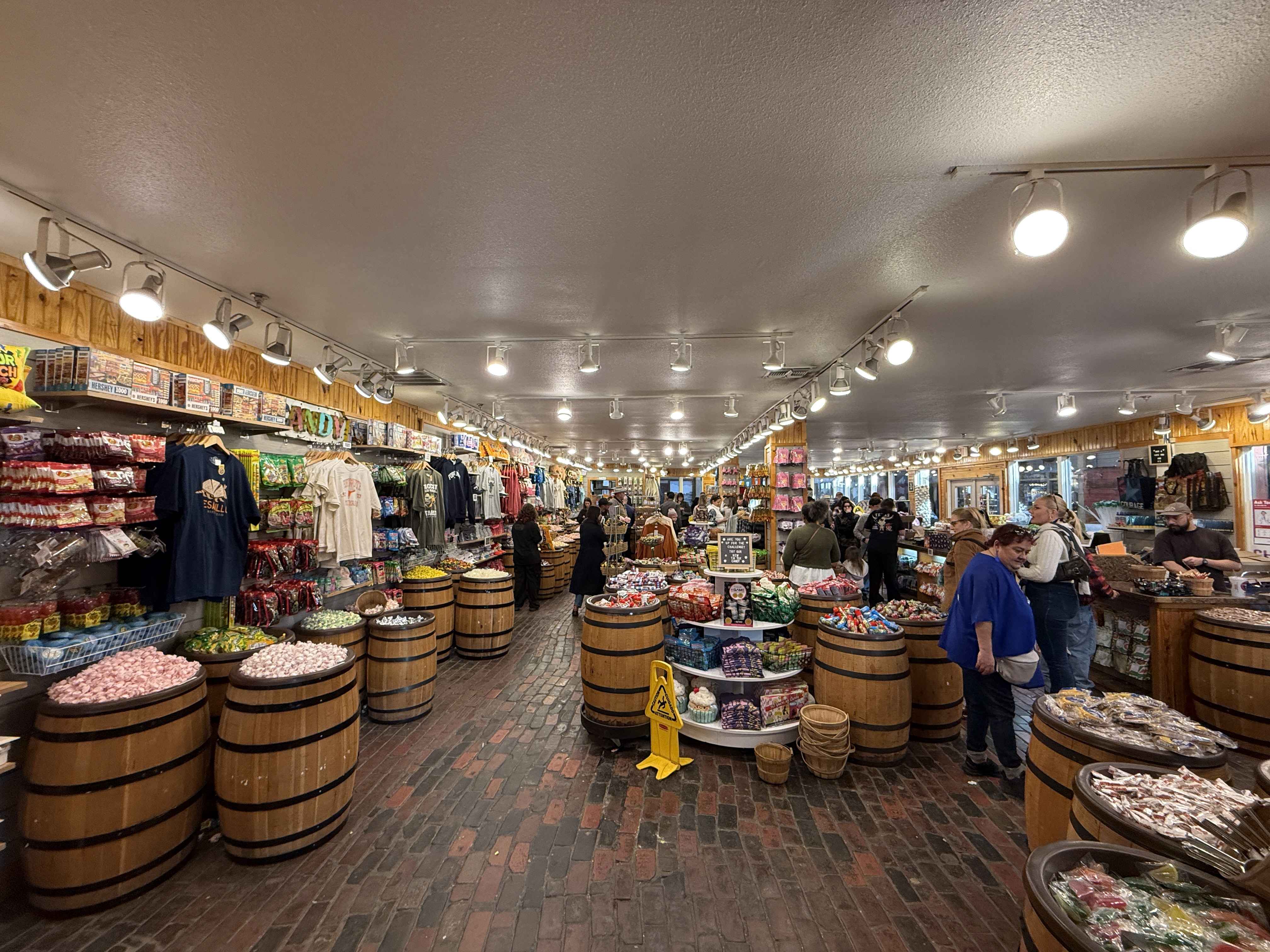 Interiér obchodu CANDY, sudy s bonbóny, suvenýry a lidé nakupují