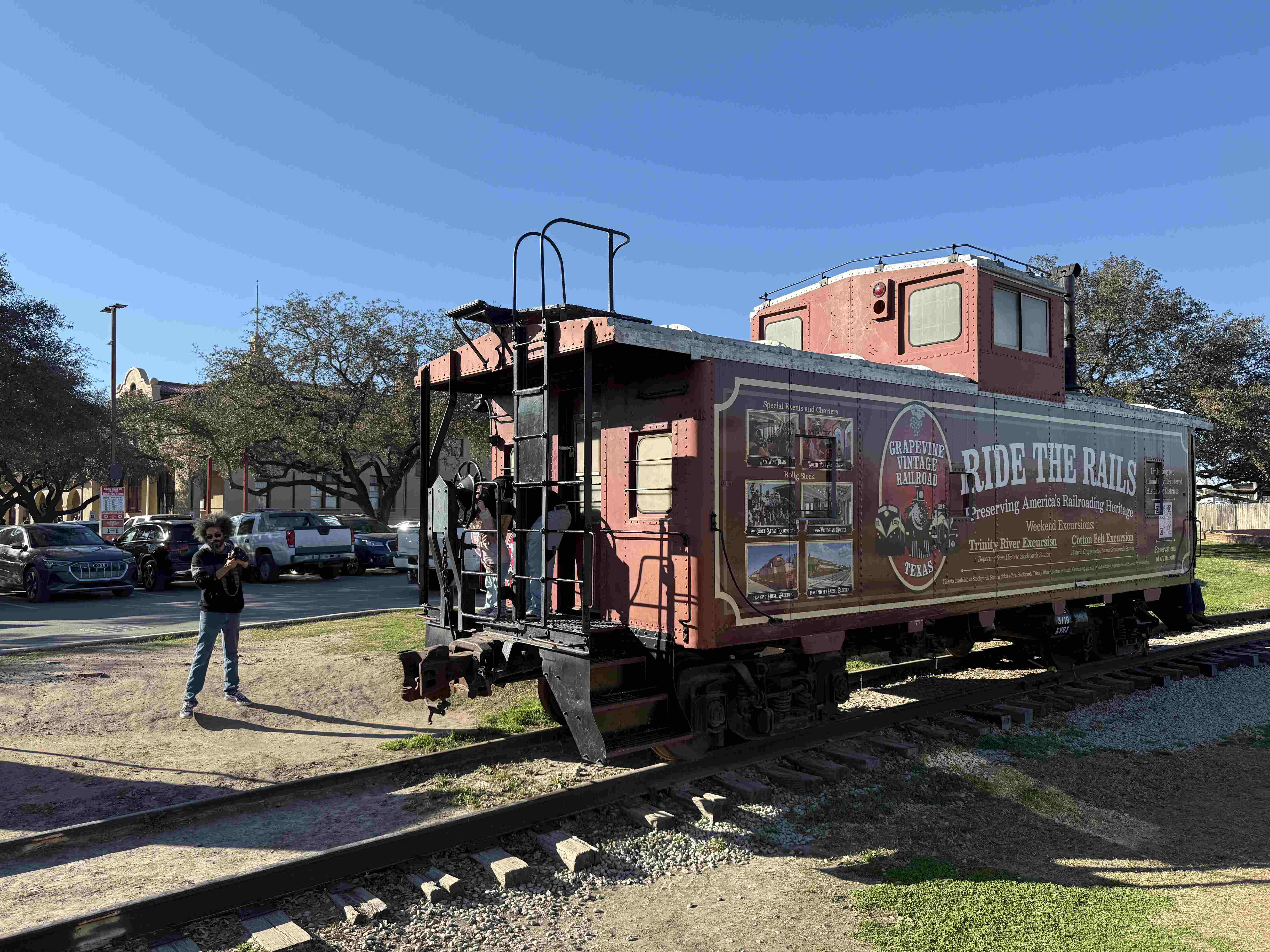 Červený vagón Grapevine Vintage Railroad na kolejích, nápis RIDE THE RAILS