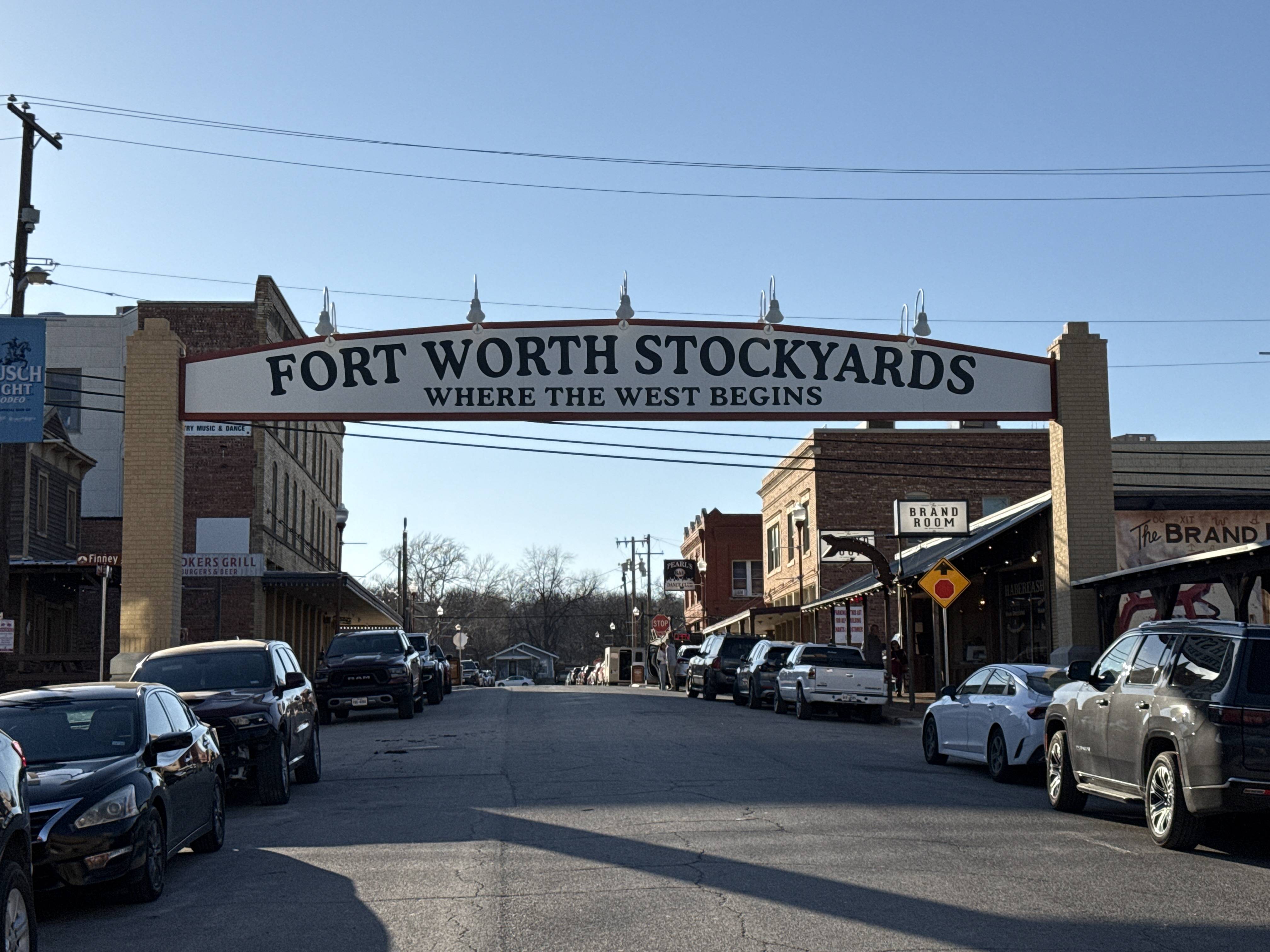 Vjezdová brána s nápisem FORT WORTH STOCKYARDS WHERE THE WEST BEGINS nad ulicí