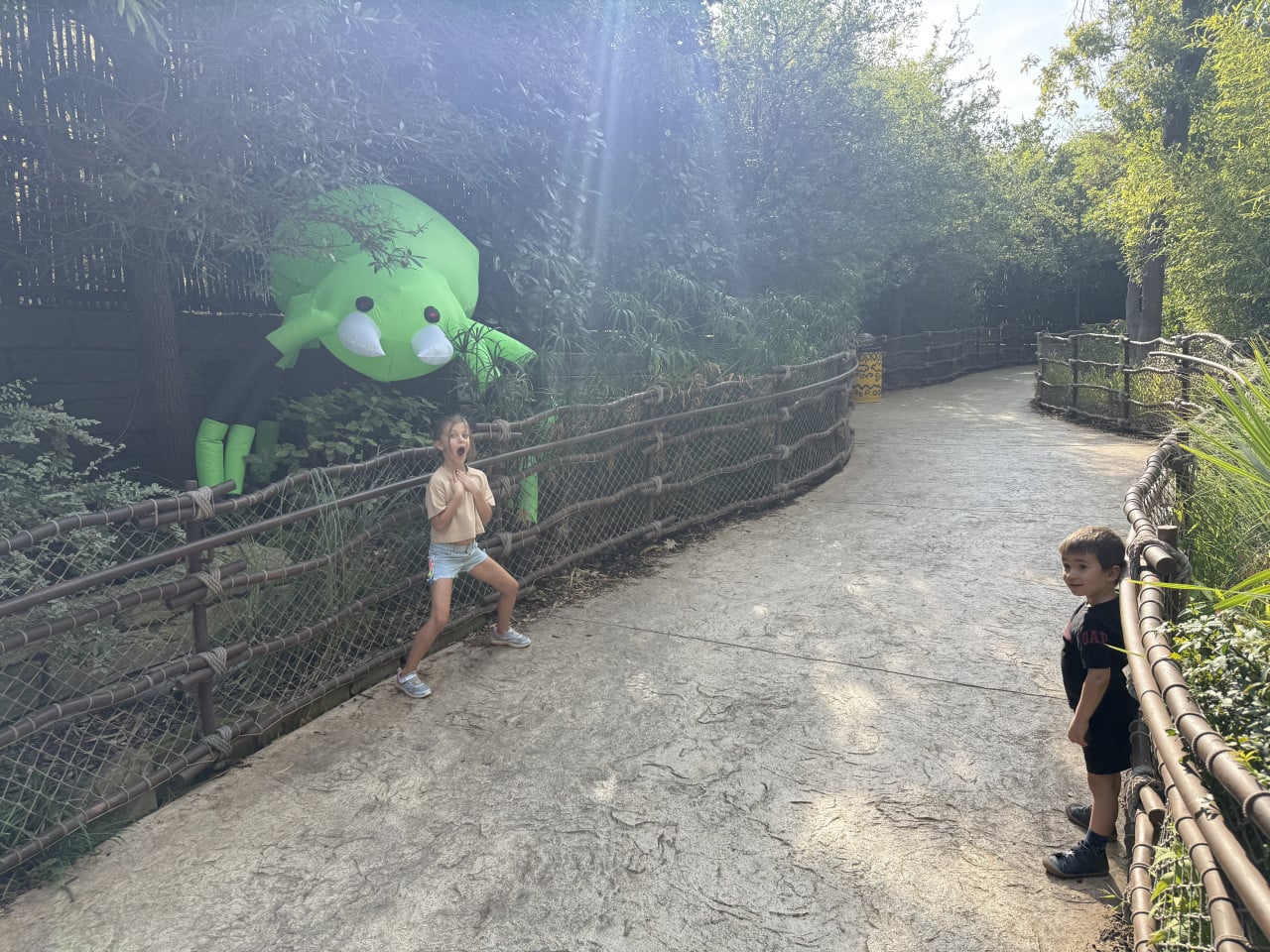 Děti na zoo stezce u velké zelené chobotnice v zeleni.