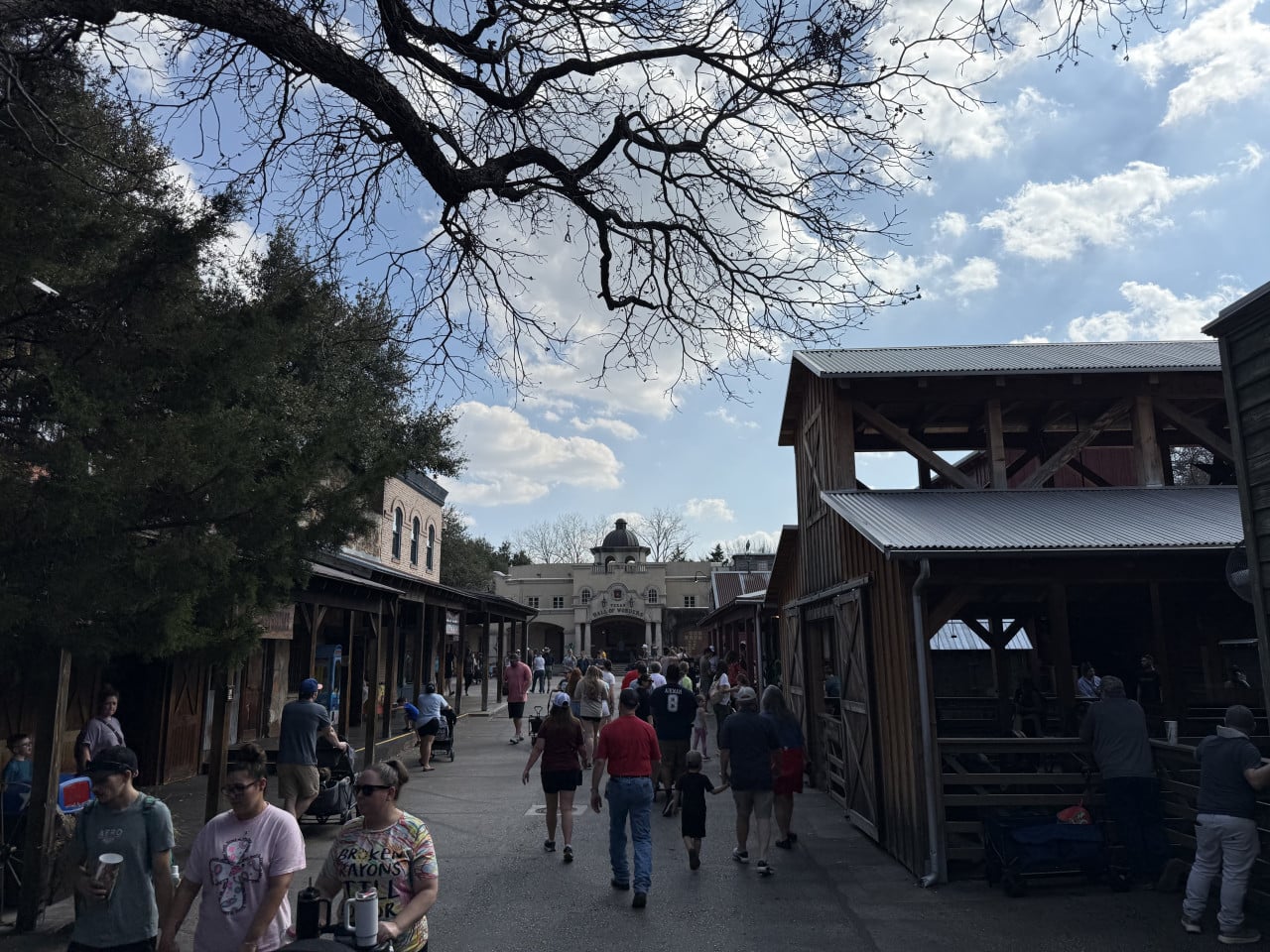 Návštěvníci procházejí westernovou částí zoo s budovou Texas Hall of Wonders.