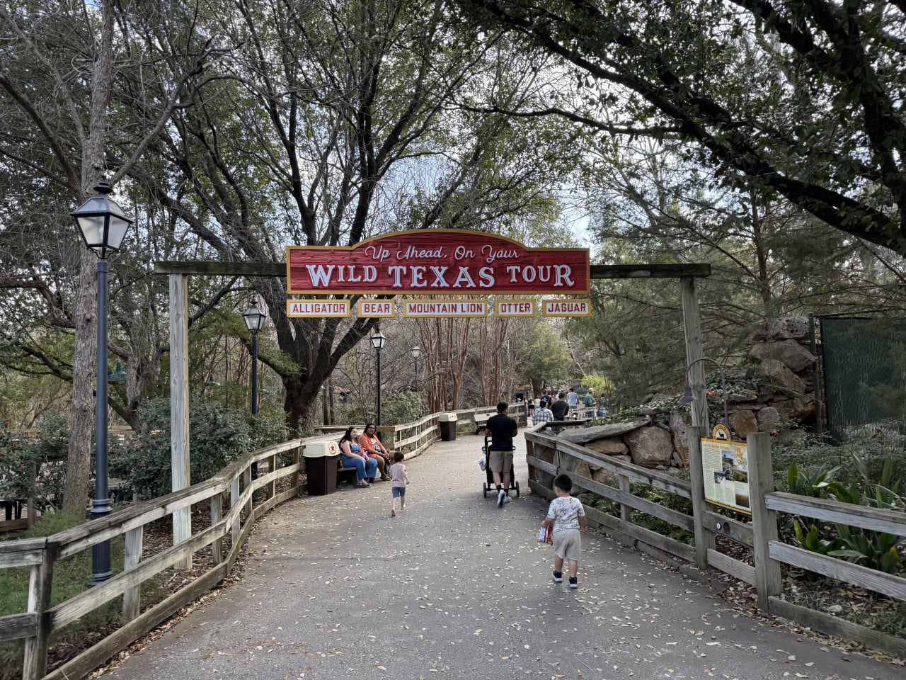 Vstup do Wild Texas Tour v zoo, lidé procházejí pod dřevěným nápisem.