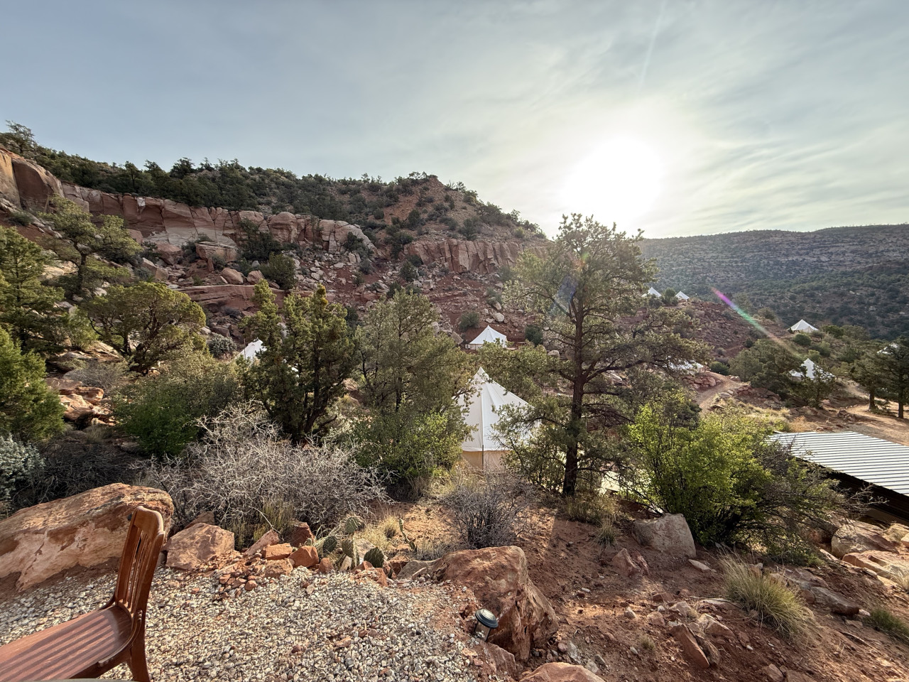 Bílé glampingové stany mezi stromy v červeném kaňonu při západu slunce.
