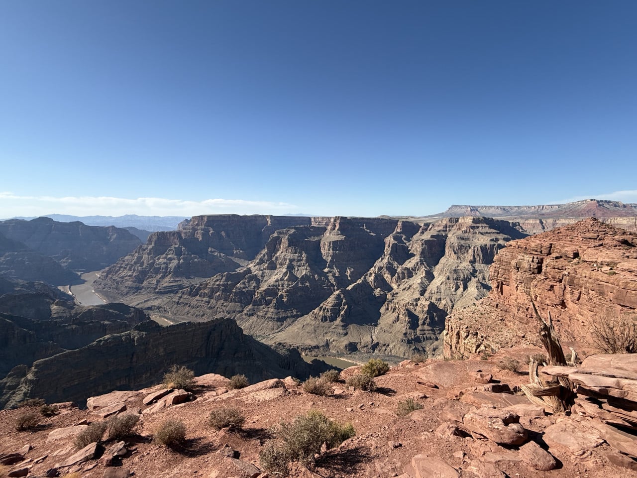 Pohled na Grand Canyon s řekou, skalními stěnami a modrou oblohou