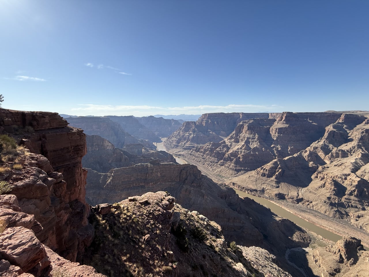 Pohled na Grand Canyon s řekou Colorado a skalnatými stěnami pod modrou oblohou
