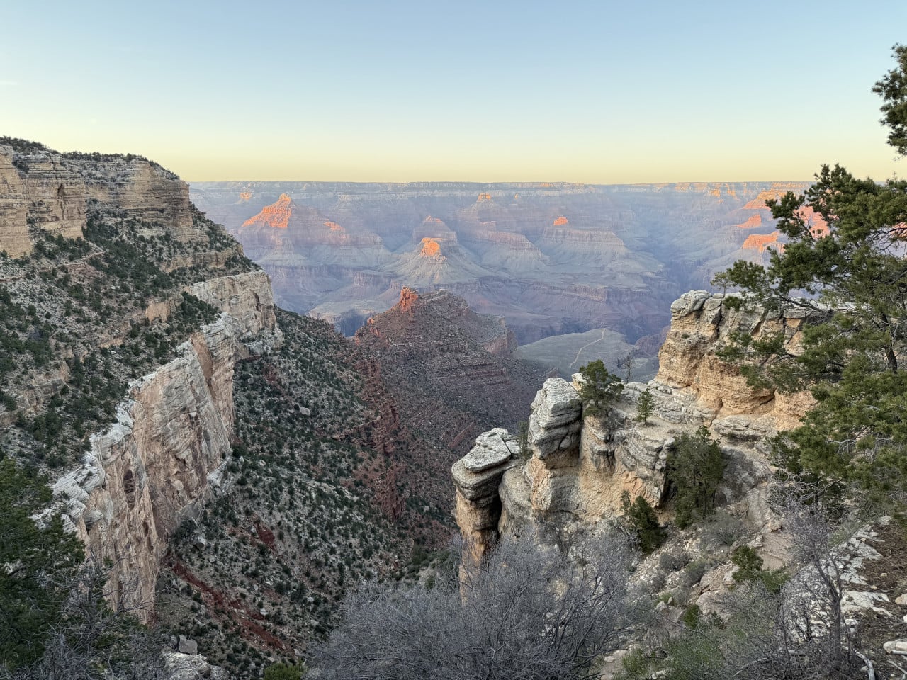 Pohled na Grand Canyon z trailu, skalní stěny a ranní světlo na útesech