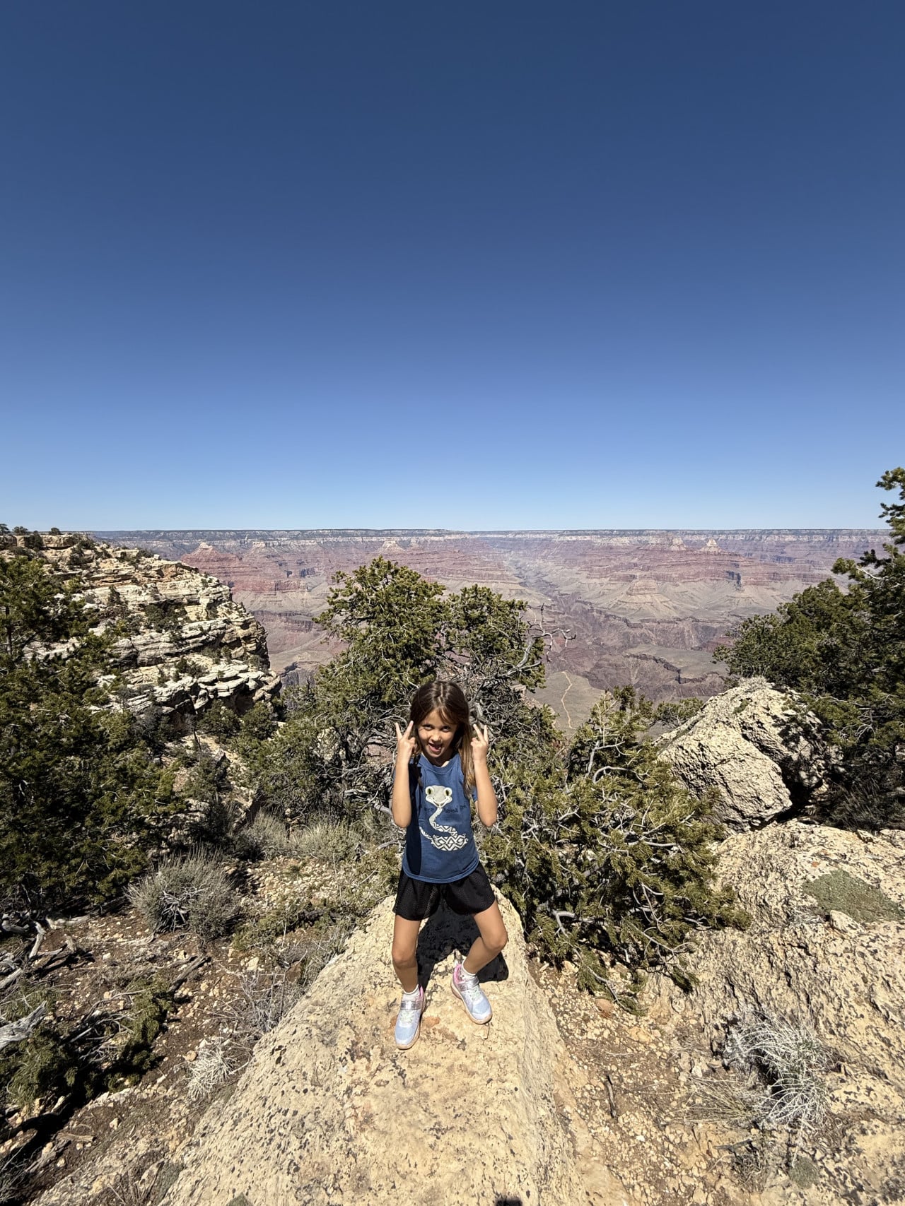 Holčička stojí na skále nad Grand Canyonem s výhledem do údolí.