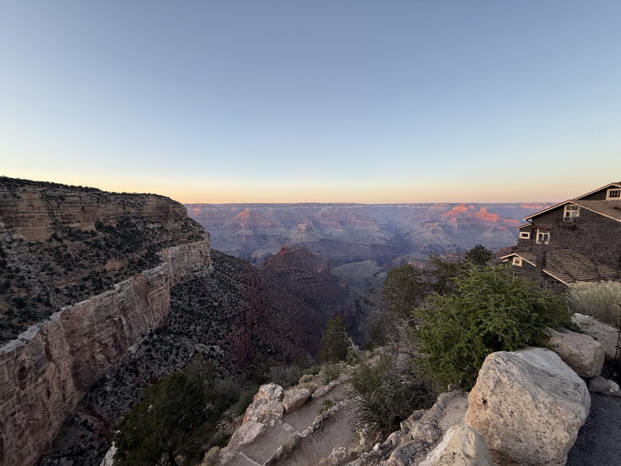 Pohled na Grand Canyon za úsvitu, s budovou na okraji útesu.