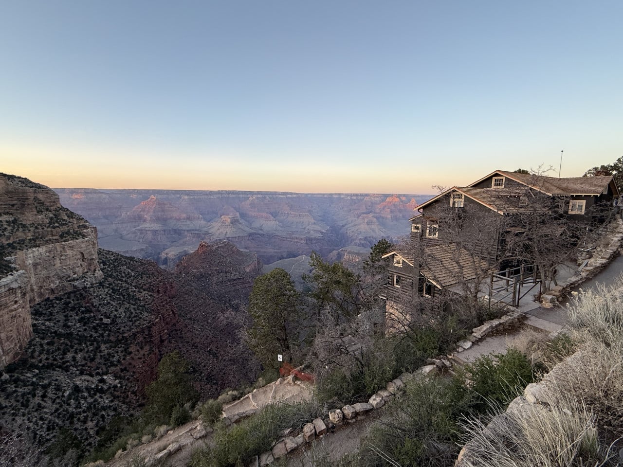 Grand Canyon s budovou hotelu na okraji kaňonu při východu slunce