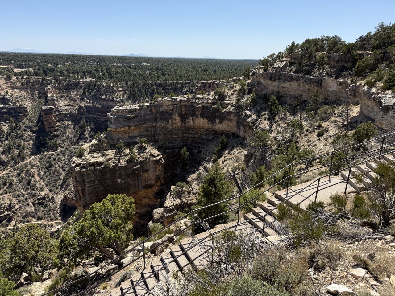 Stezka s kamennými schody a zábradlím nad skalnatým kaňonem Grand Canyonu