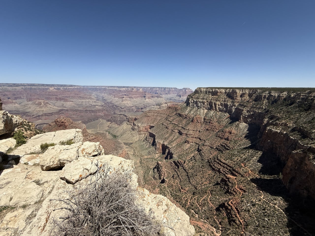 Výhled na Grand Canyon z trailu u Maricopa Point, skalnatý okraj a hluboké údolí under clear sky