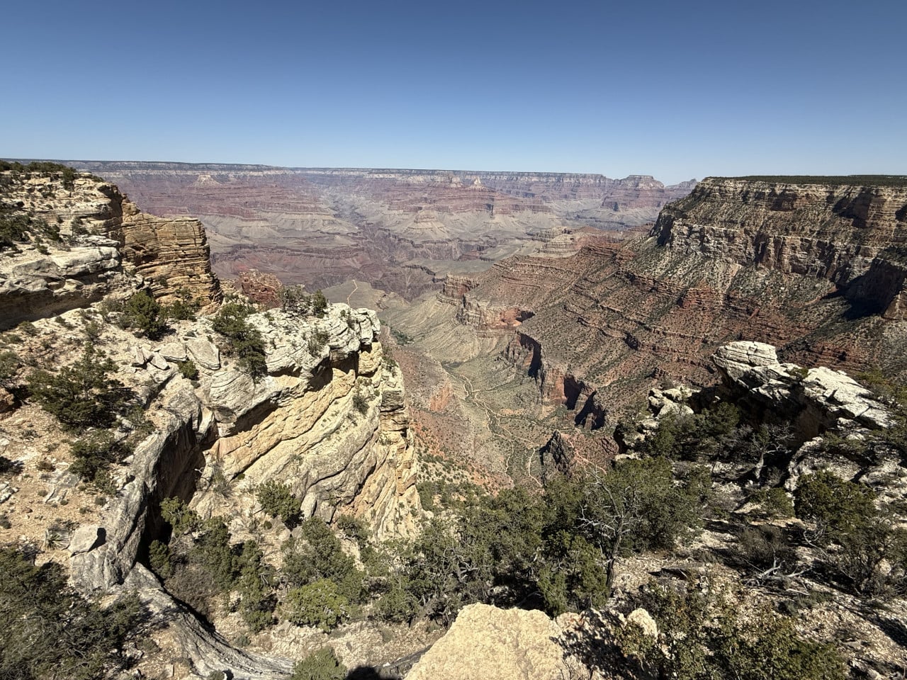 Pohled na Grand Canyon z útesu s cestou v údolí a skalními stěnami.