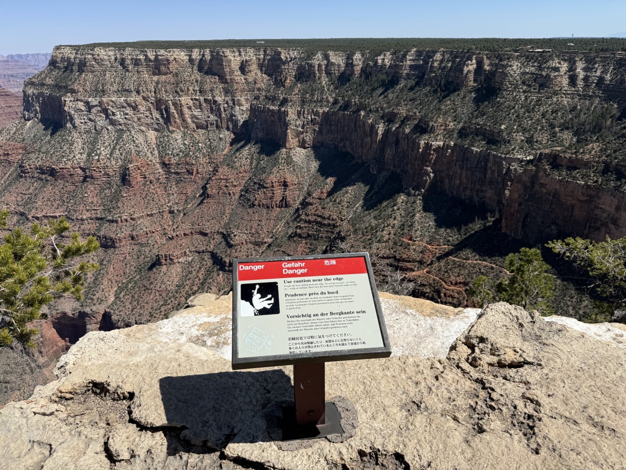 Výhled na Grand Canyon s varovnou cedulí Danger na okraji útesu