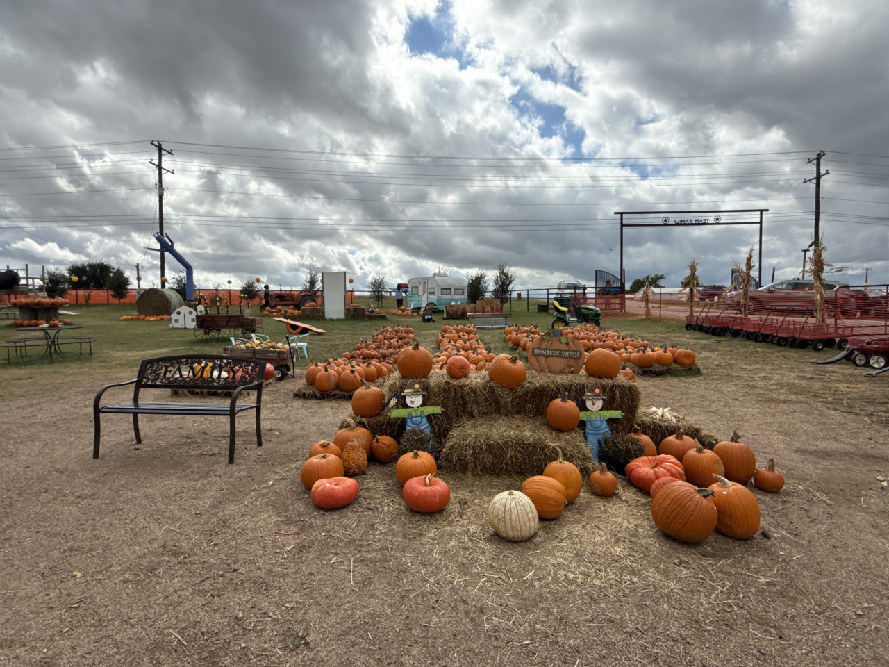 Americký pumpkin patch s hromadami dýní, senem a podzimní výzdobou pod zamračenou oblohou