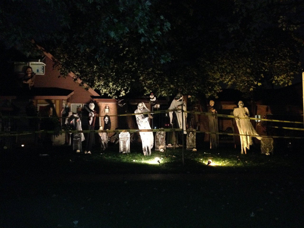Noční dům s děsivými strašidly a páskami Caution na halloweenské zahradě