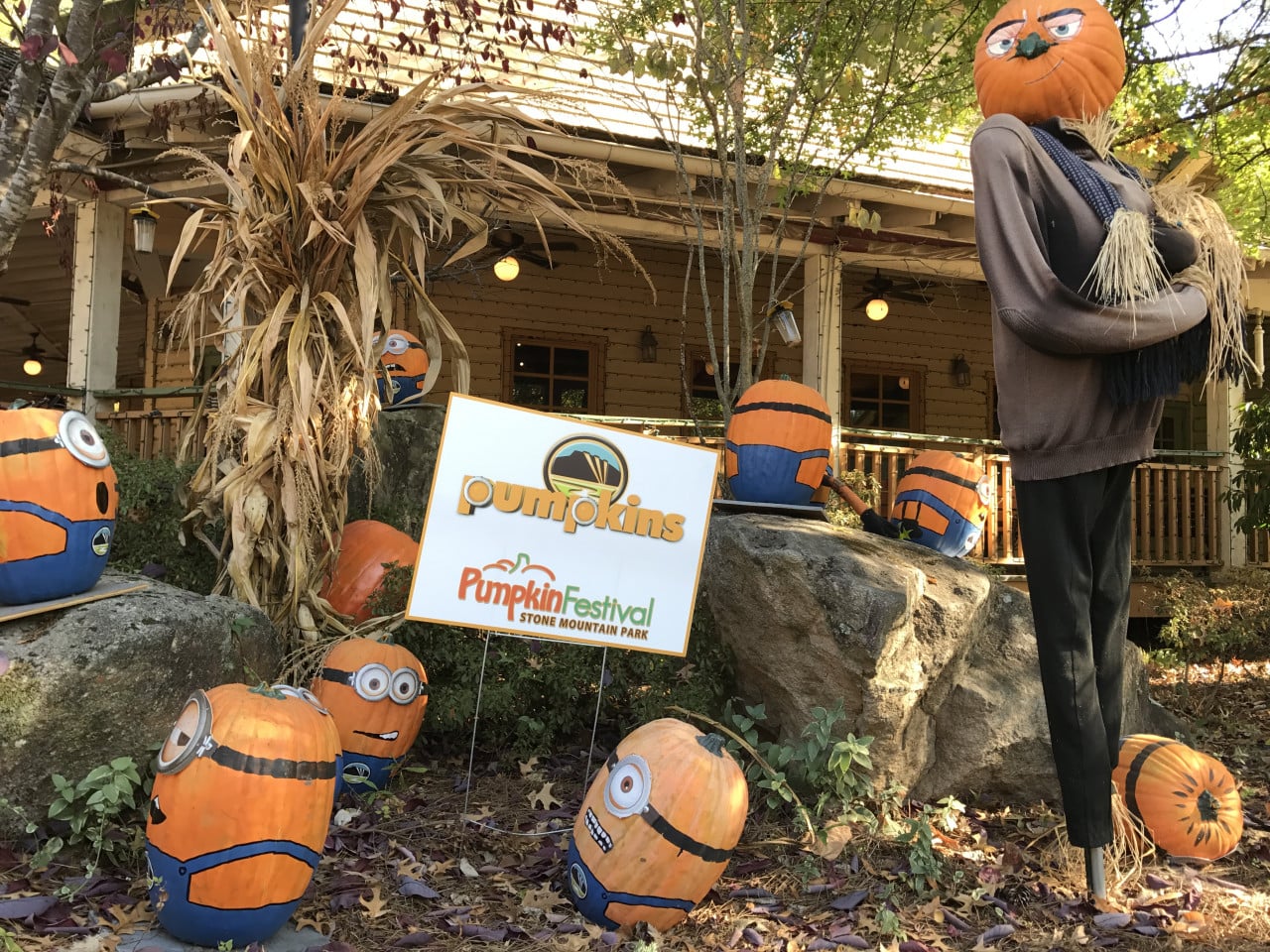 Halloweenová dekorace s dýněmi, strašákem a nápisem Pumpkin Festival u domu.