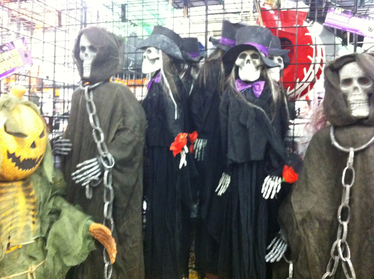 Strašidelné halloweenské kostlivé postavy s řetězy mezi dekoracemi v obchodě