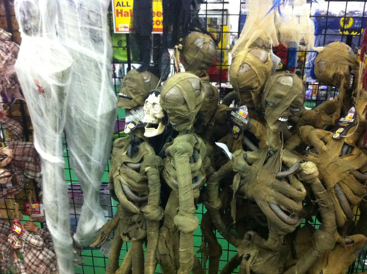 Halloweenové masky mumie a zombie na prodejním stojanu ve strašidelném obchodě.