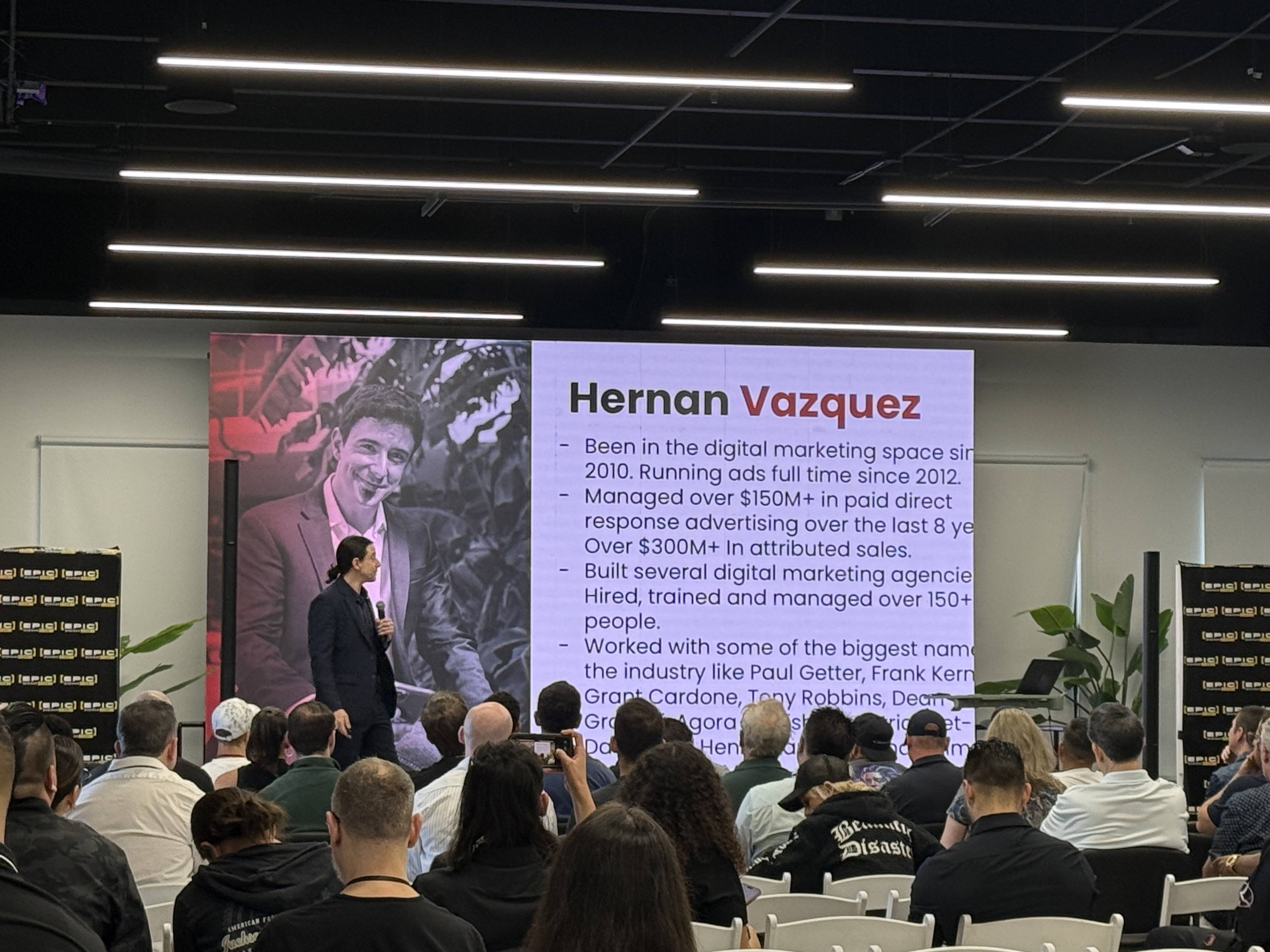 Přednášející před publikem, na plátně slide s textem Hernan Vazquez