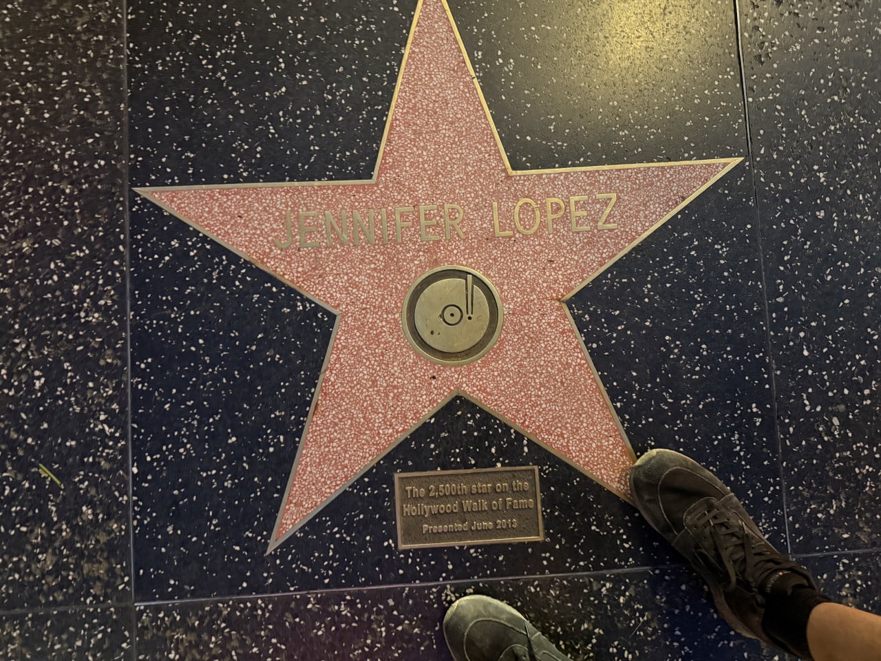 Hvězda Jennifer Lopez na Hollywood Walk of Fame, nohy turistů v rohu.