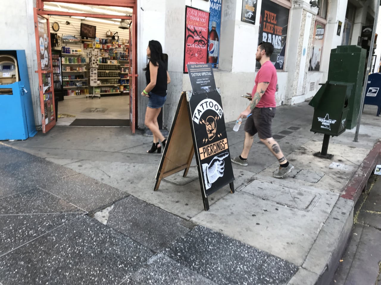 Lidé procházejí kolem tetovacího salonu s cedulí Tattoos and Piercings v Hollywoodu.