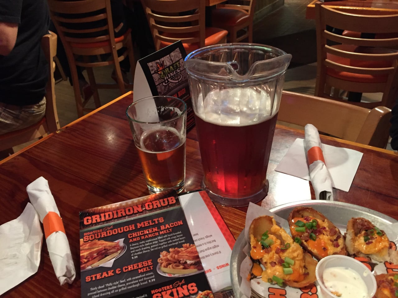 Džbán a sklenice piva na stole, menu GRIDIRON GRUB a předkrm