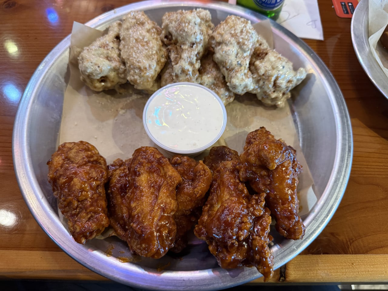 Talíř kuřecích křídel, část v BBQ omáčce, část v sýrové, dip uprostřed