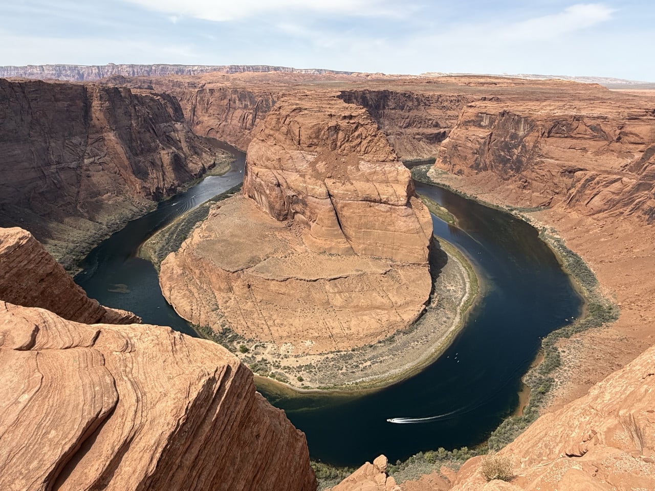 Pohled z útesu na meandr řeky Colorado, lodí a skalami Horseshoe Bend