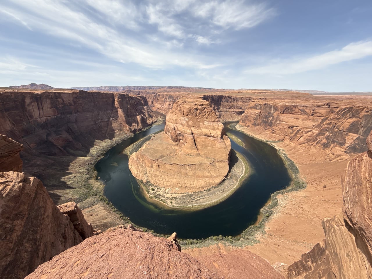 Pohled z vyhlídky na Horseshoe Bend: řeka Colorado obtáčí skalní masiv v kaňonu.
