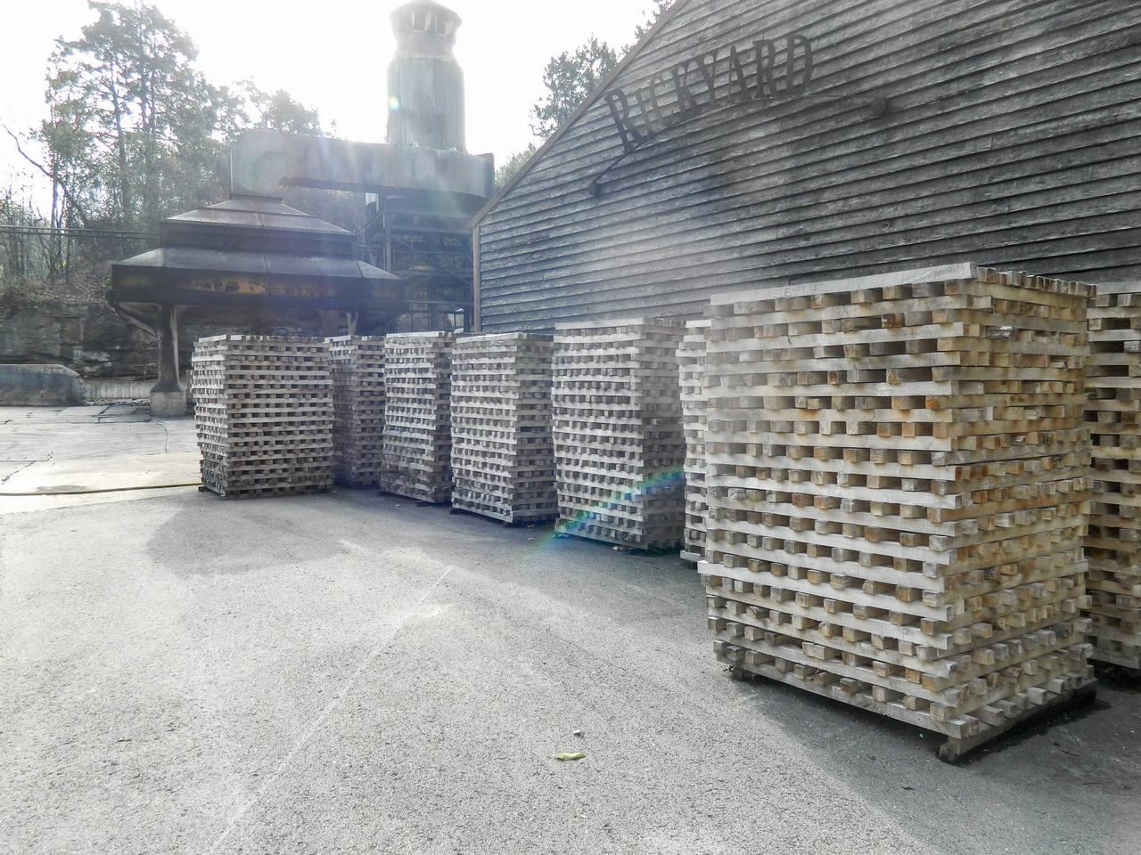 Hromady dřevěných hranolů na dvoře, v pozadí budova s nápisem CYPRESS.