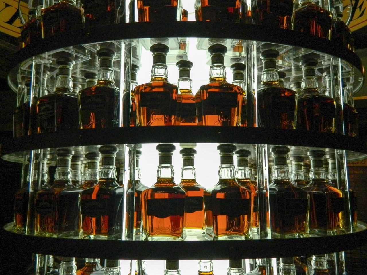 Osvětlené police s řadami lahví Jack Daniel’s s jantarovou whisky.