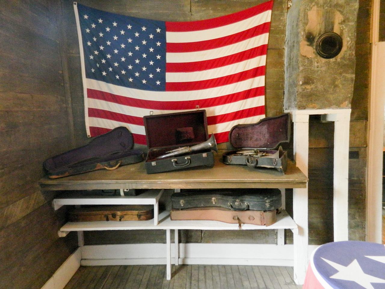 Americká vlajka na zdi, police se starými kufry a pouzdry na nástroje