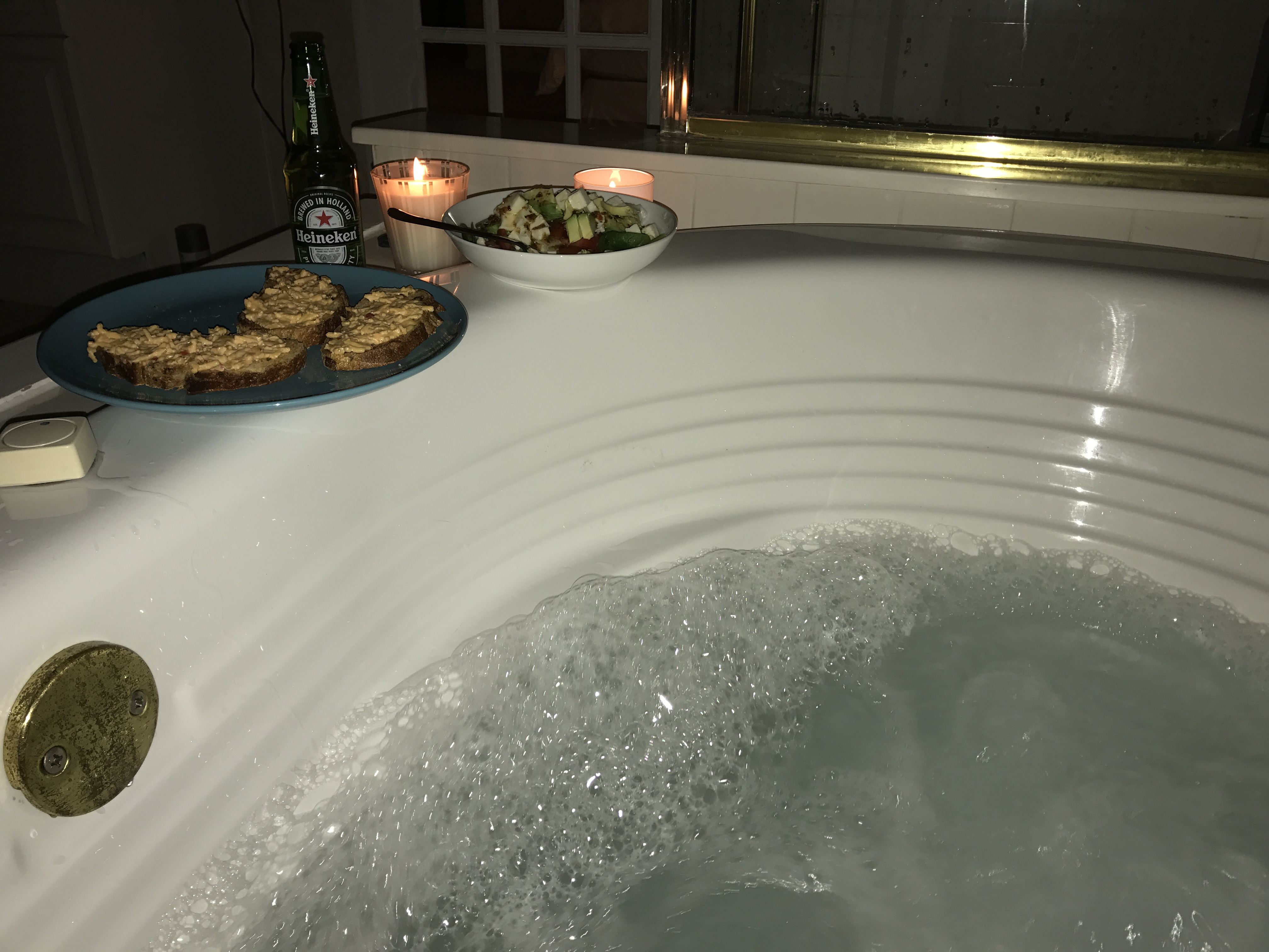 Vana s bublající vodou, svíčky, chlebíčky, salát a láhev Heineken