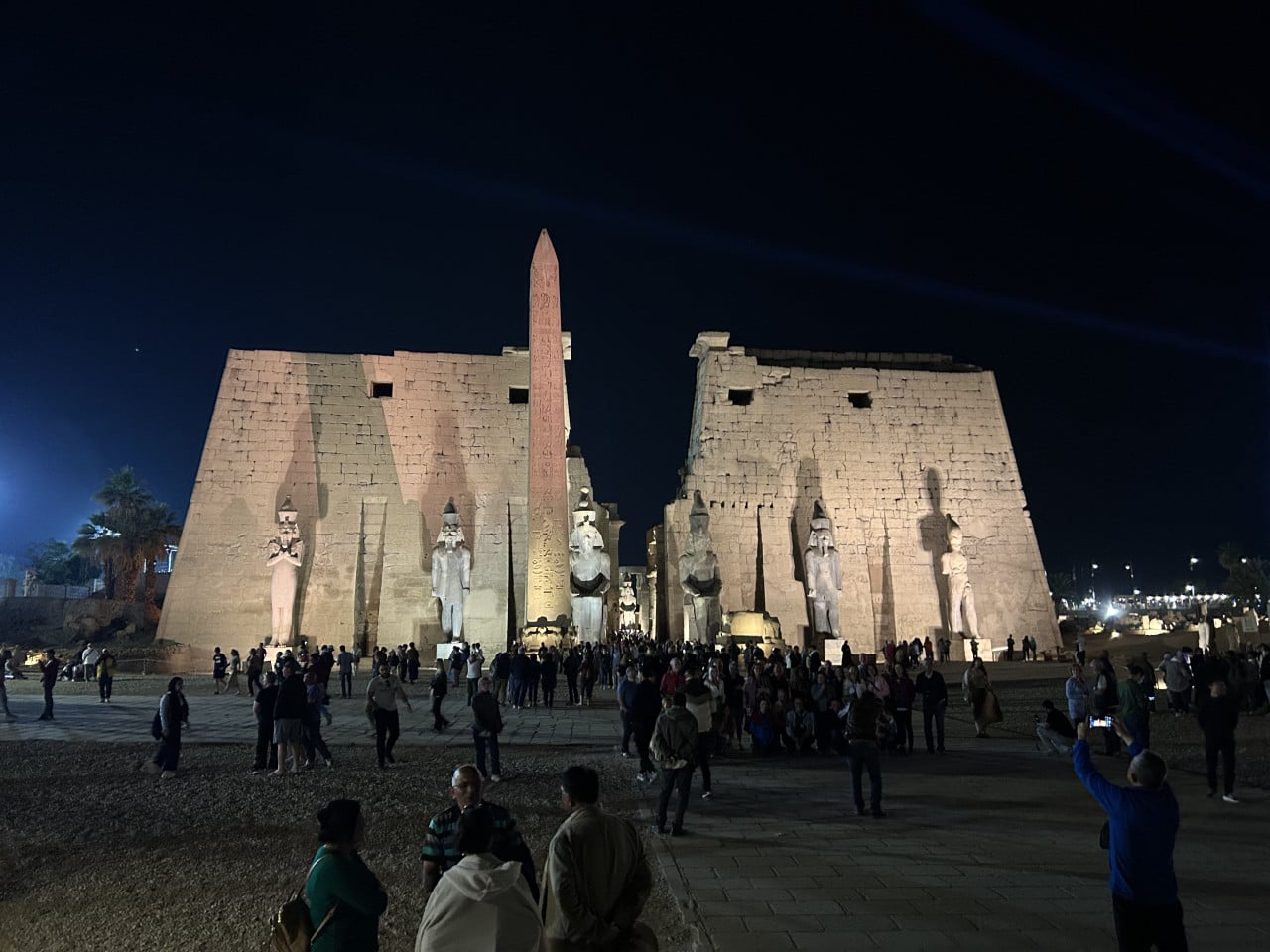 Noční vstup do chrámu Karnak s obeliskem, sochami a turisty