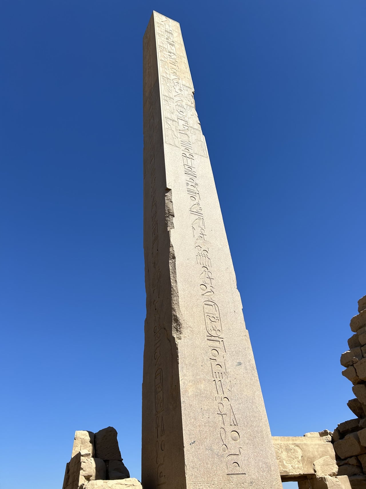 Vysoký egyptský obelisk s hieroglyfy proti modré obloze šroubovanýto a nepřeložitelně není správně?