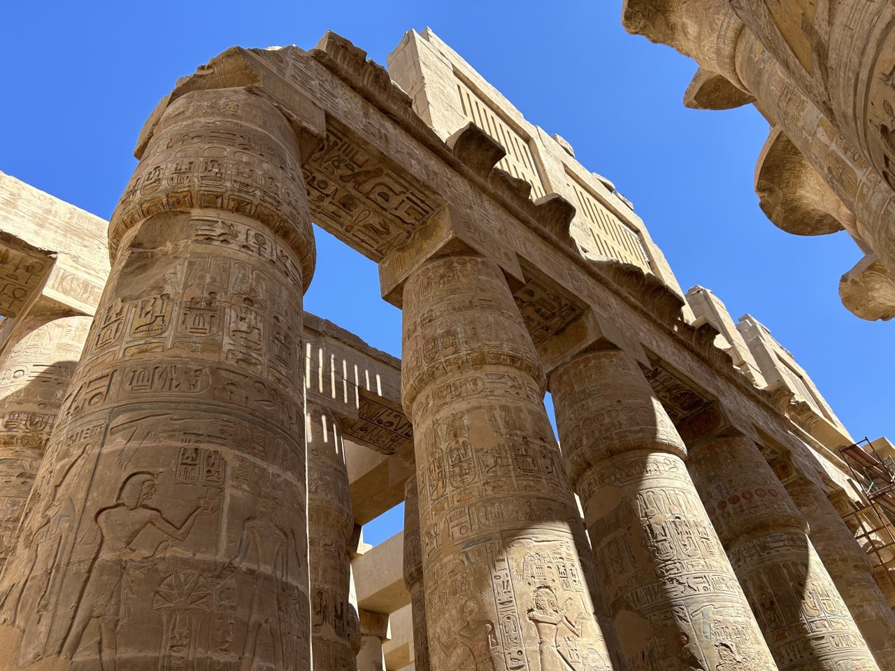 Monumentální egyptské sloupy s hieroglyfy proti modré obloze