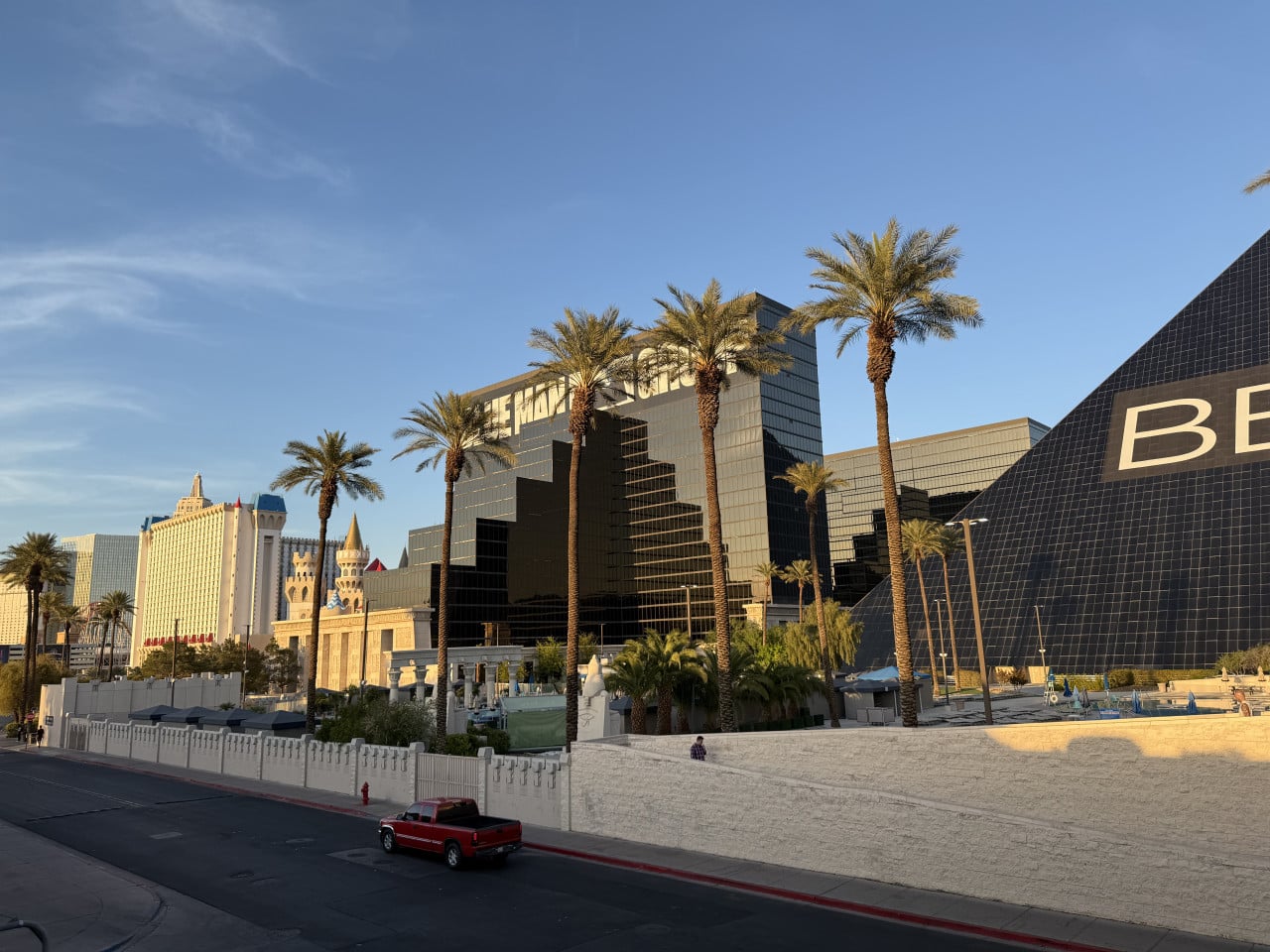 Palmami lemovaný Las Vegas Strip, budova s nápisem DELAY a pyramida BE.