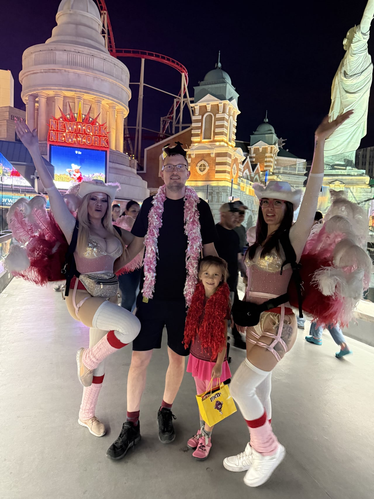 Muž a dítě se dvěma tanečnicemi, nápis NEW YORK NEW YORK, taška m&m's.