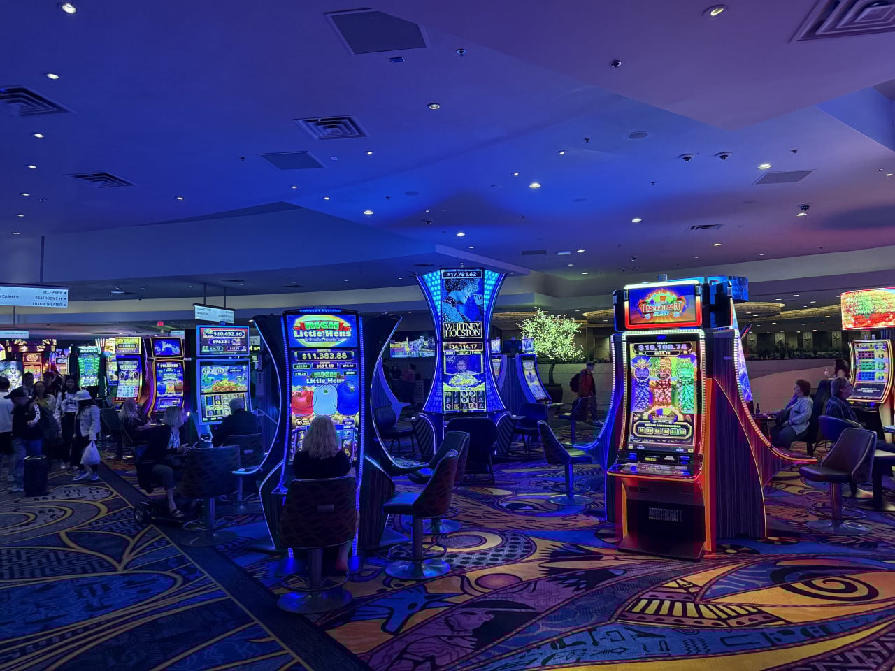 Interiér kasina se světelnými automaty Whitney Houston, Little Hen, Bachelorette Blast a hráči.