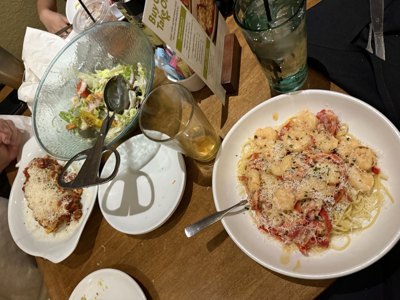 Stůl s těstovinami s krevetami, salátem, nápoji a menu Build Your Taco.