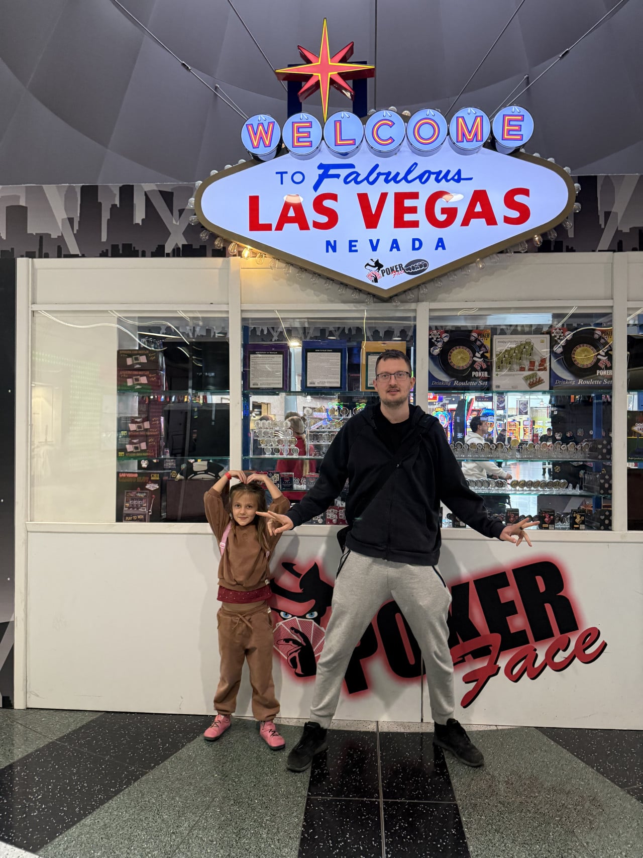 Muž a dítě pózují pod nápisem WELCOME to Fabulous LAS VEGAS NEVADA, Poker Face.