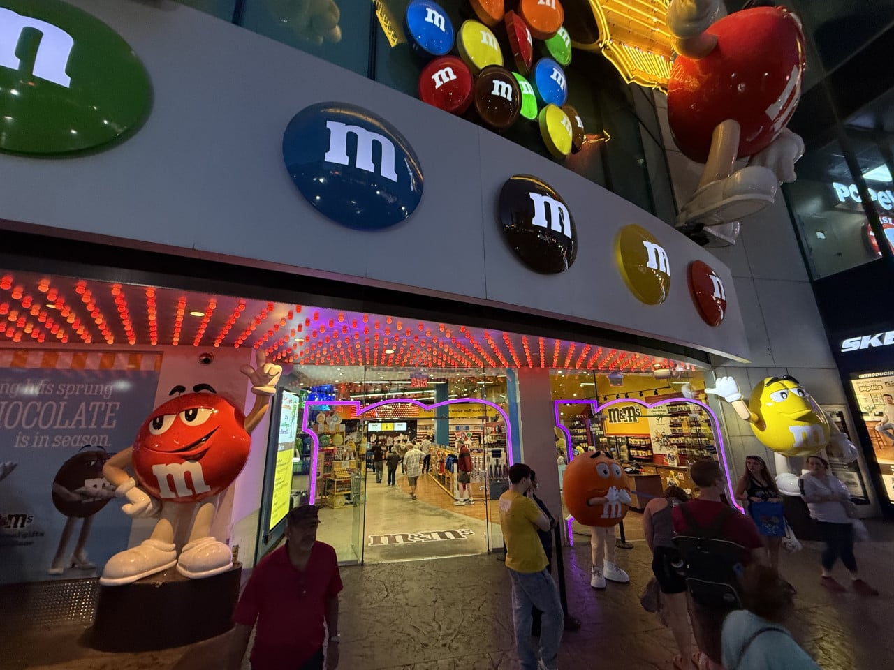 Vchod do obchodu M&M’s ve Vegas, barevná loga a obří maskoti bonbonů.